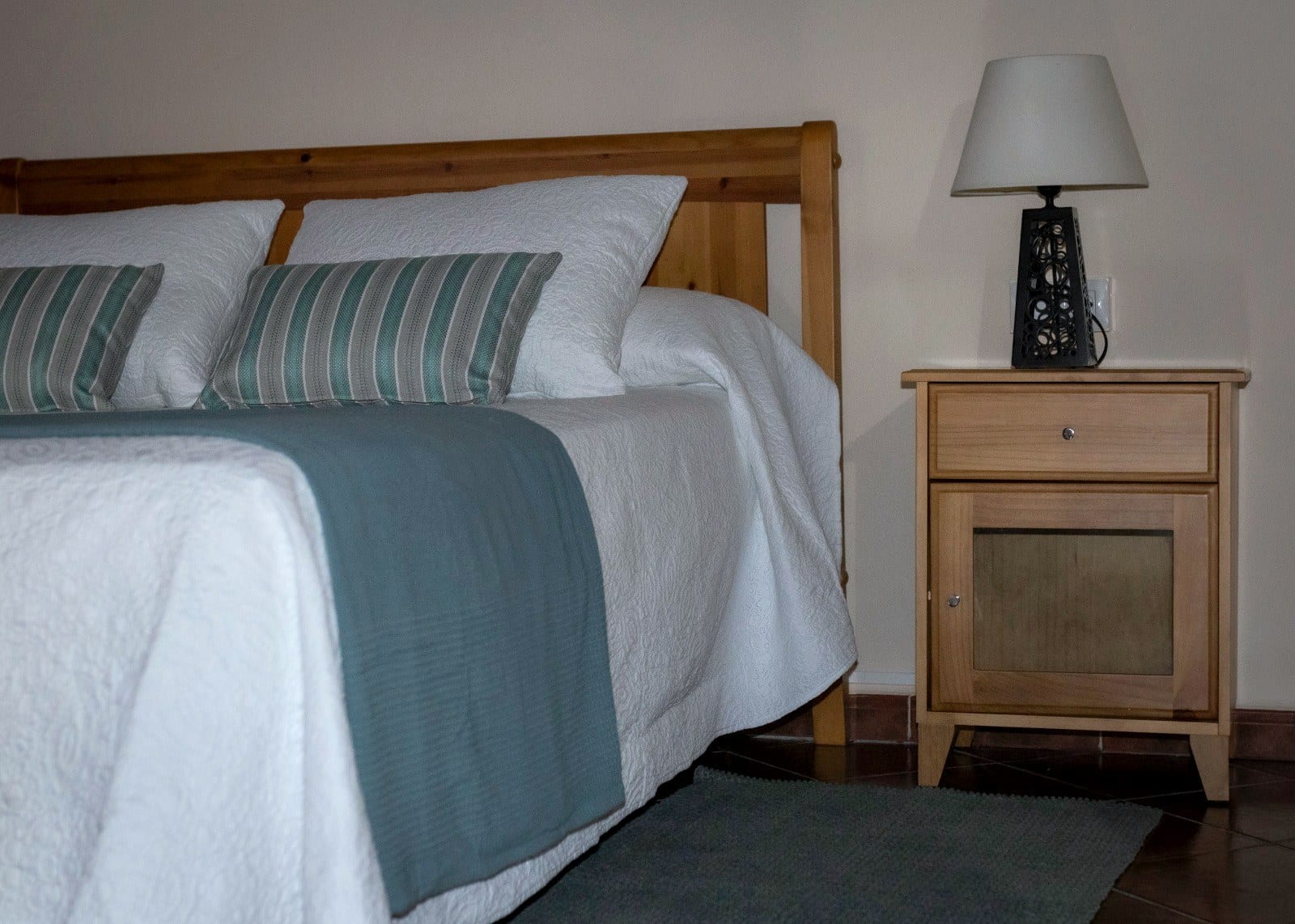 Mesilla de madera clara con lámpara de forja junto a la cama en un dormitorio de Finca Julia