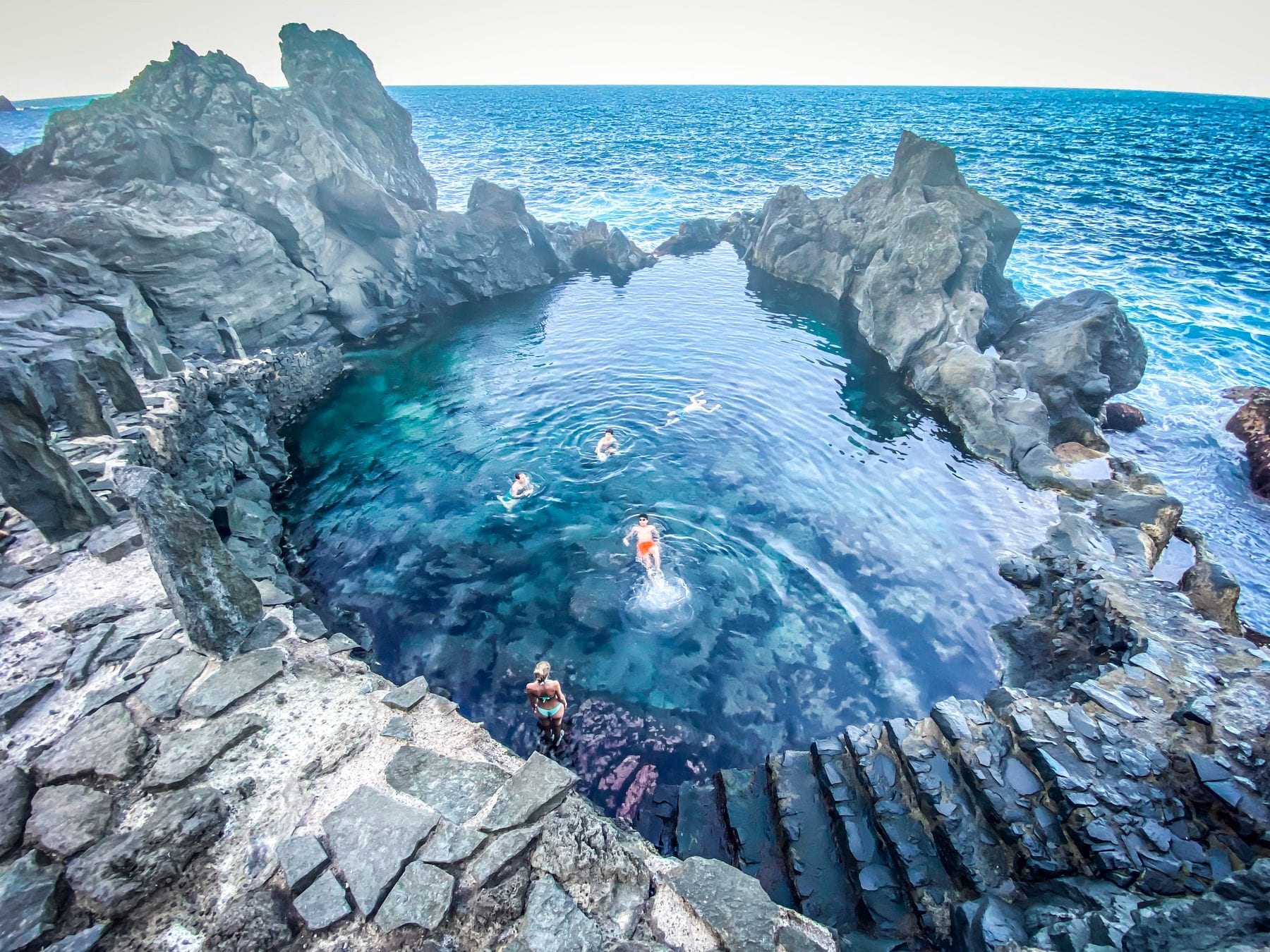 Piscina natural del Charco del Viento entre coladas de lava, con bañistas